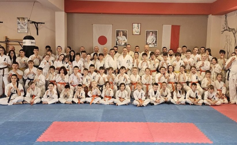 Duża grupa zawodników karate w kimonach na macie sportowej