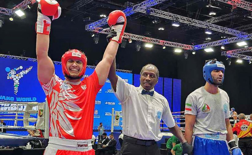 Maks Palej na ringu z uniesionymi rękami w geście zwycięstwa, obok sędzia i przeciwnik