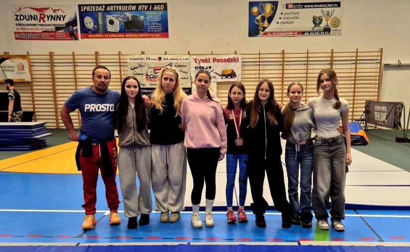 grupa zawodniczek z trenerem na hali sportowej