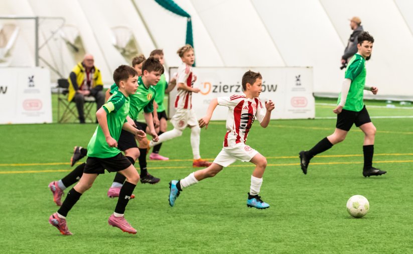 Młodzi piłkarze podczas meczu, obok sędzia