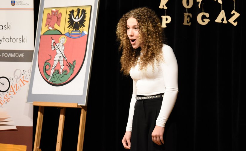 Dziewczyna w bałej bluzce i w kręconych włosachpodczas recytacji