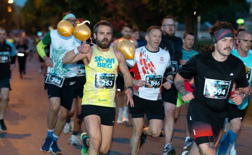 Kilkanaście osób biegnących nocą po ulicy