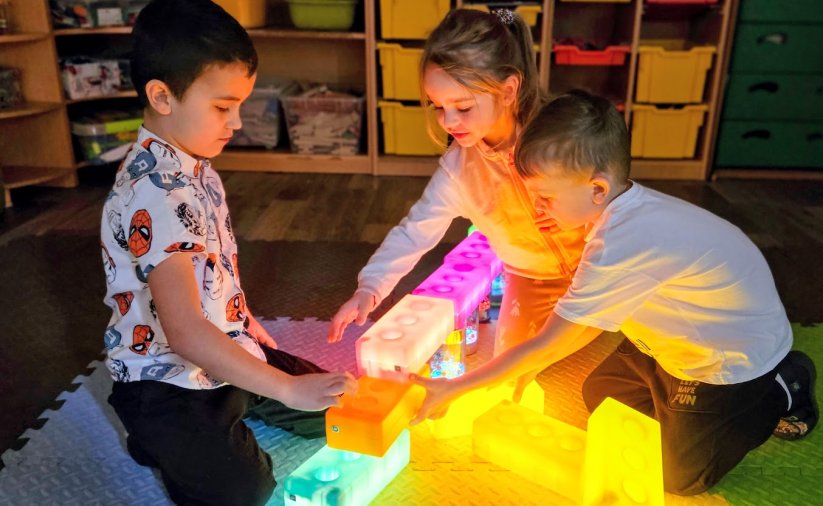 troje dzieci bawiących się świecącymi klockami