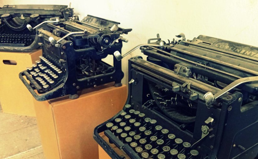 Trzy stare maszyny do pisania na kartonowych pudełkach