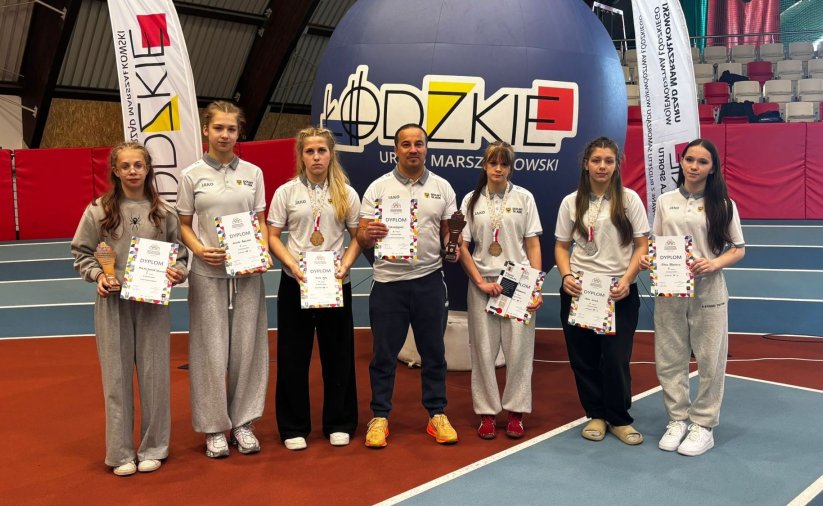 Sześć zapaśniczek w hali sportowej, pośrodku trener