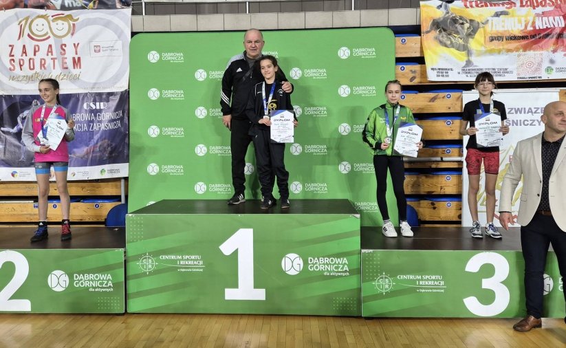 Zawodniczki stojące na zielonym podium z medalami i dyplomami