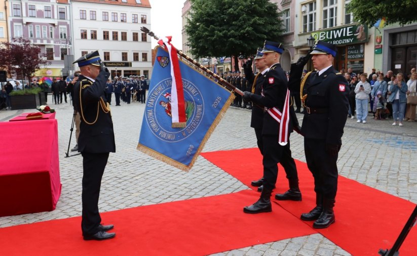 Oficer straży pożarnej salutuje przed sztandarem
