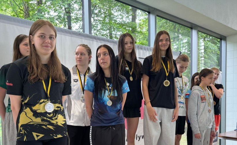 Grupa pływaczek na wspólnym zdjęciu, każa ma na szyi medal
