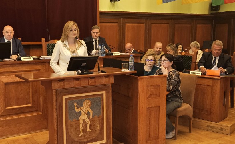 Przewodnicząca rady przy mównicy, za nią przy stole dwóch wiceprzewodniczących, po prawej burmistrz