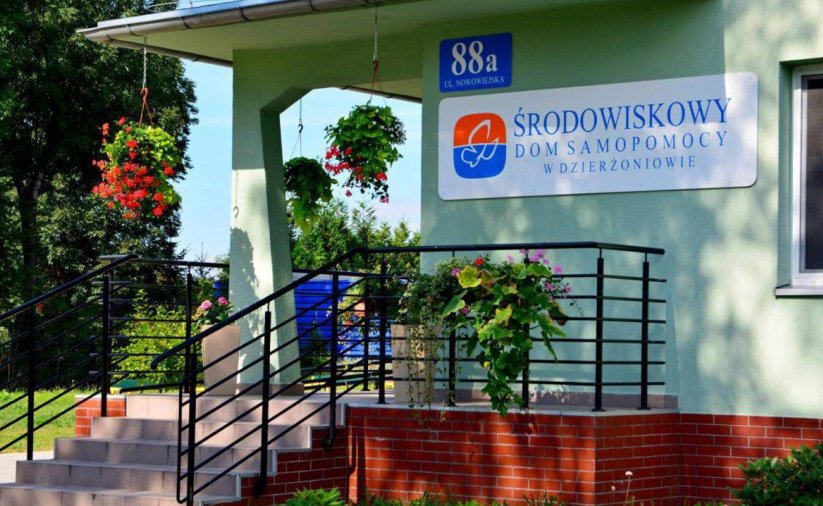Wejście po schodach prowadzące tarasem do budynku, na ścianie napis Środowiskowy Dom Samopomocy