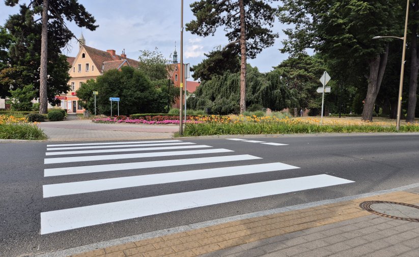 Przejście dla pieszych zaraz po namalowaniu, za przejściem mała kamienica i park