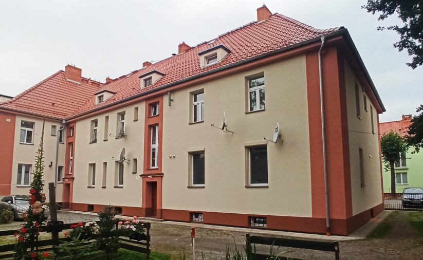 Dwupiętrowa kamienica z odnowioną elewacją w piaskowym kolorze z brązowymi elementami