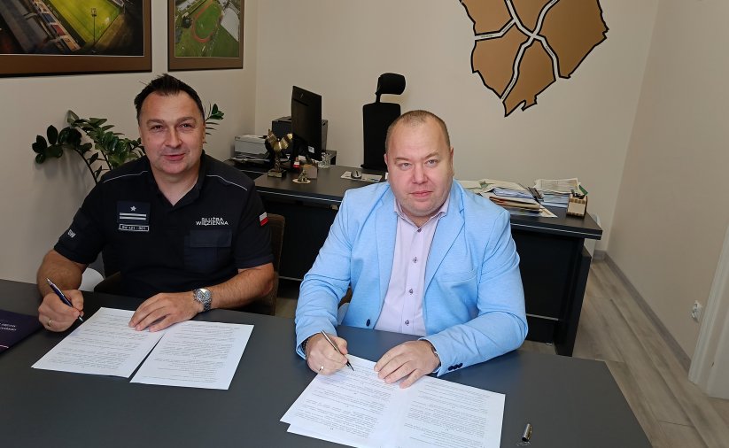 Zastępca burmistrza i komendant aresztu przy biurku podpisują porozumienie
