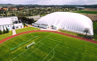 Boisko piłkarskie i biała hala sportowa wyglądająca jak balon