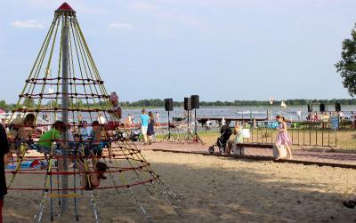 Plaża piaszczysta przy Zalewie Zegrzyńskim, na pierwszym planie dzieci bawiące się na placu zabaw