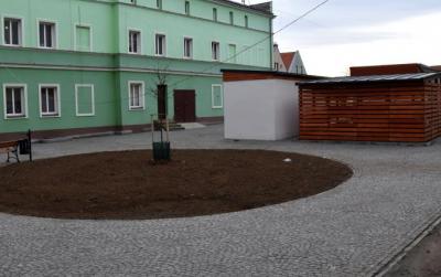 Widok na zieloną kamienicę i miejsce do segregacji odpadów