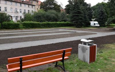 Nowa łąwka i kosz na śmieci, w tle miejsce na owocowy skwer
