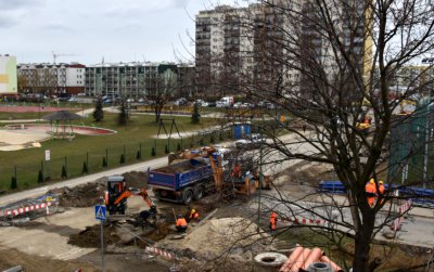 Skrzyżowanie dróg osiedlowych widziane z góry, w tle wieżowce