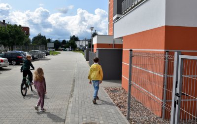 Dzieci przed wejśćiem do budynku, w drugim planie droga