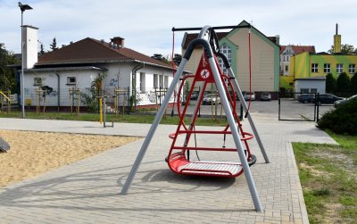Huśtawka dla osób z niepełnosprawnoscią, w tle budynek
