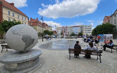 Kamienny duzyt globus na Rynku, obok ludzie siedzący na ławkach