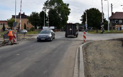 Samochody przejeżdżające przez tory, w tle budynki