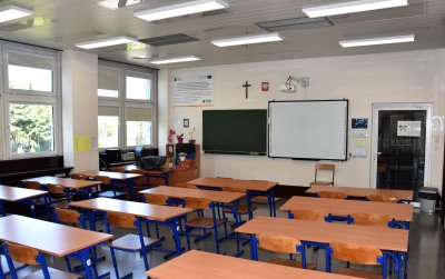 Klasa szkolna, puste ławki i krzesła, na wprost tablica multimedialna