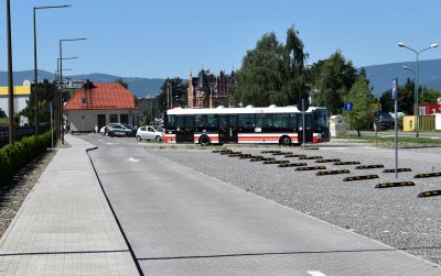Duży parking przy cmentarzu, na końcu stojący autobus komunikacji miejskiej