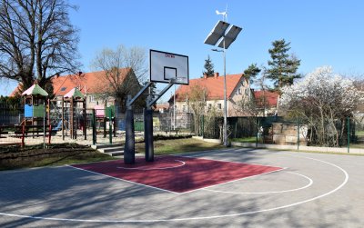 Boisko do kosza z kostki maiennej, za nim plac zabaw