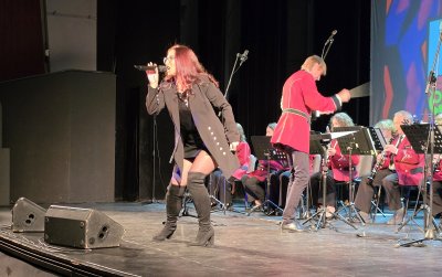 Orkiestra dęta w czasie koncertu, przed nią wokalistka