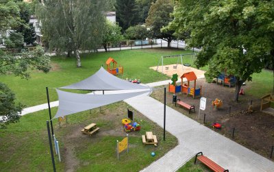 Pgród z placem zabaw dla dzieci, część zasłonięta płachtami dającymi cień