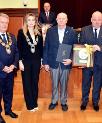 Kazimierz Janeczkoodbierający tytuł Zasłużony dla Miasta Dzierżoniowa, obok burmistrz i przewodniczący rady miejskiej