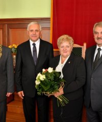 Jolanta Oliwa z bukietem kwiatów, obok burmistrz przwodniczący i wiceprzewodniczący rady miejskiej