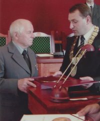 Piotr Mielnik odbierający medal z rąk przewodniczącego rady