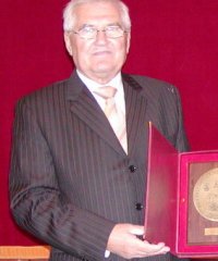 Zbigniew Chmura stoi trzymając w ręku duży okrągły medal