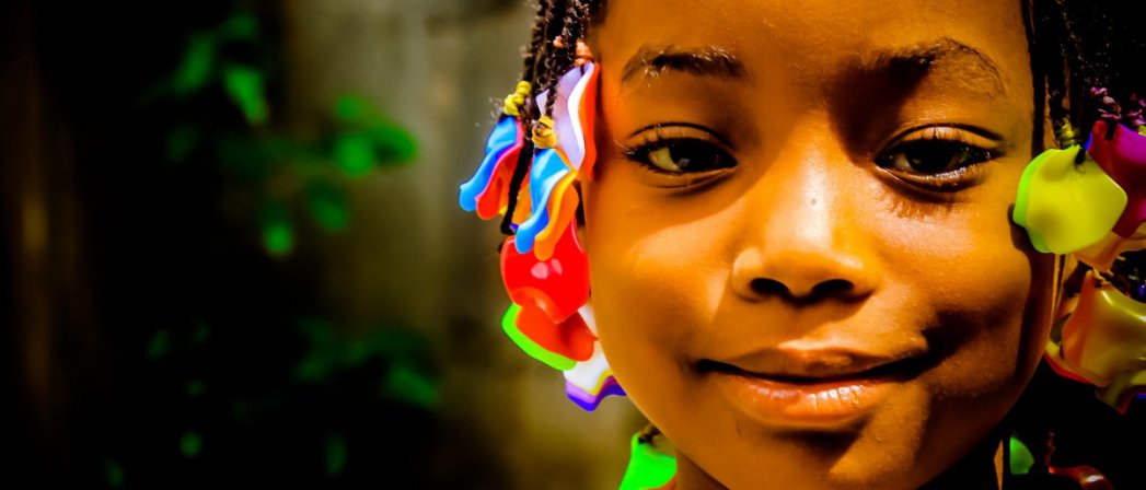 Twarz afrykańskiej dziewczynki z kolorowymi kokardami we włosach