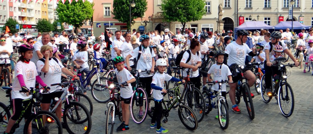 Duża grupa dorosłych i dzieci z rowerami na rynku