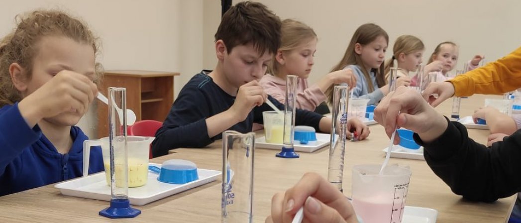 Młodzi ludzie przy ławkach przeprowadzający doświadczenia chemiczne