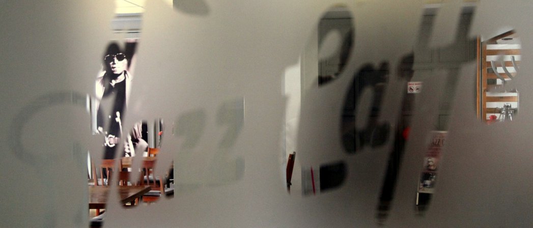 Matowa szyba, za nią zdjęcie muzyka z trąbką