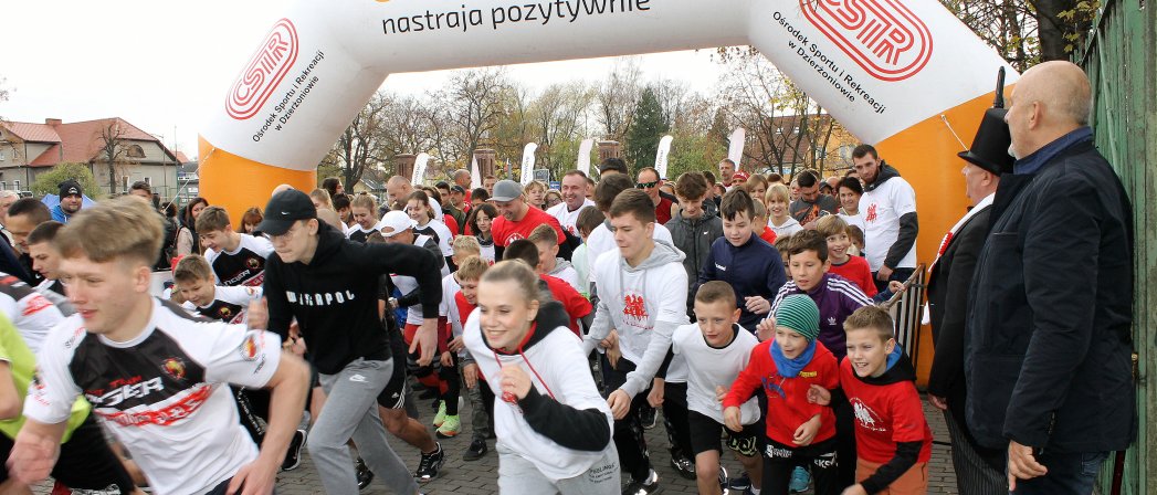 Tłum uczestników przebiega przez dmuchaną bramę startową, na niej napis Dizerżoniów nastraja pozytywnie