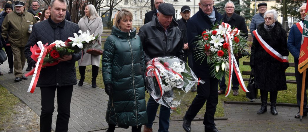 Grupa osób składająca wieńce przed pomnikiem