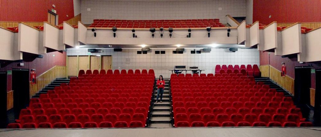Widownia dzierżoniowskiego kina, białe ściany i czerwone fotele na parterze i balkonie