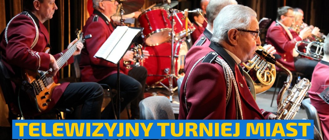 Orkiestra, muzycy w jednakowych galowych strojach grają na dużej scenie