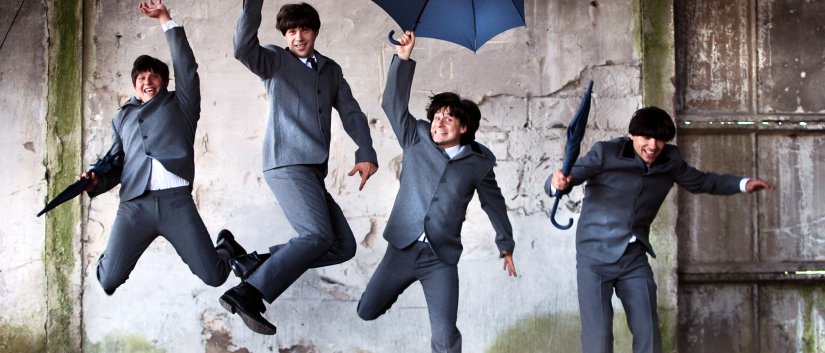 Czwórka chłopaków w garniturach i z parasolkami w rękach