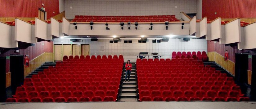 Widownia dzierżoniowskiego kina, białe ściany i czerwone fotele na parterze i balkonie