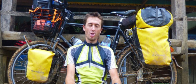 Daniel Kocuj siedzący na ziemi w żółtym stroju rowerowym, za nim rower