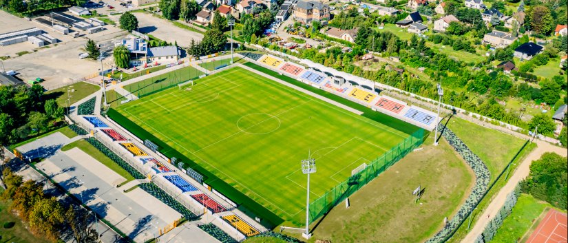 Stadion z góry, obok duży parking i plac targowy